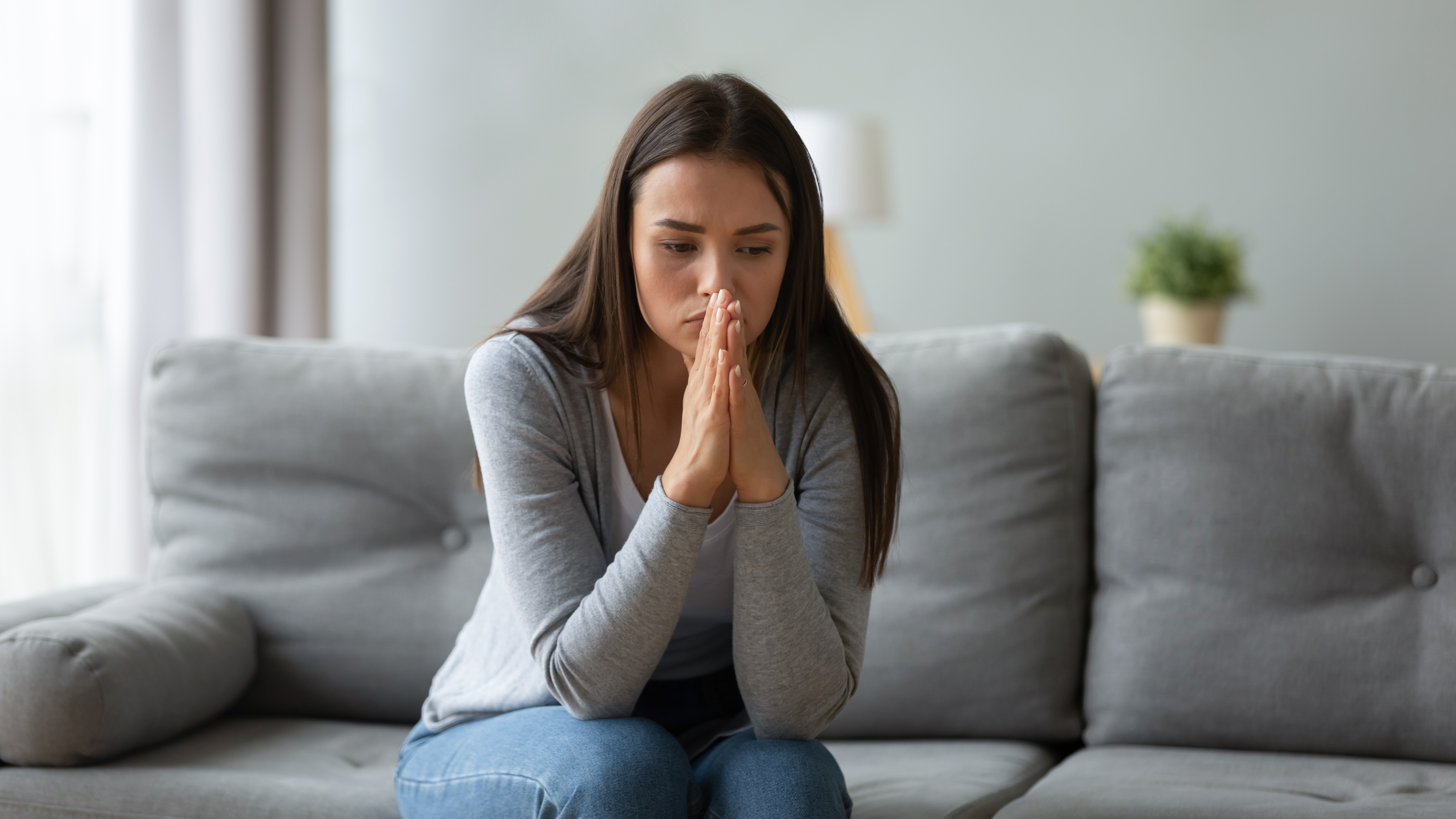 An unhappy young woman sitting on a sofa | Source: Shutterstock