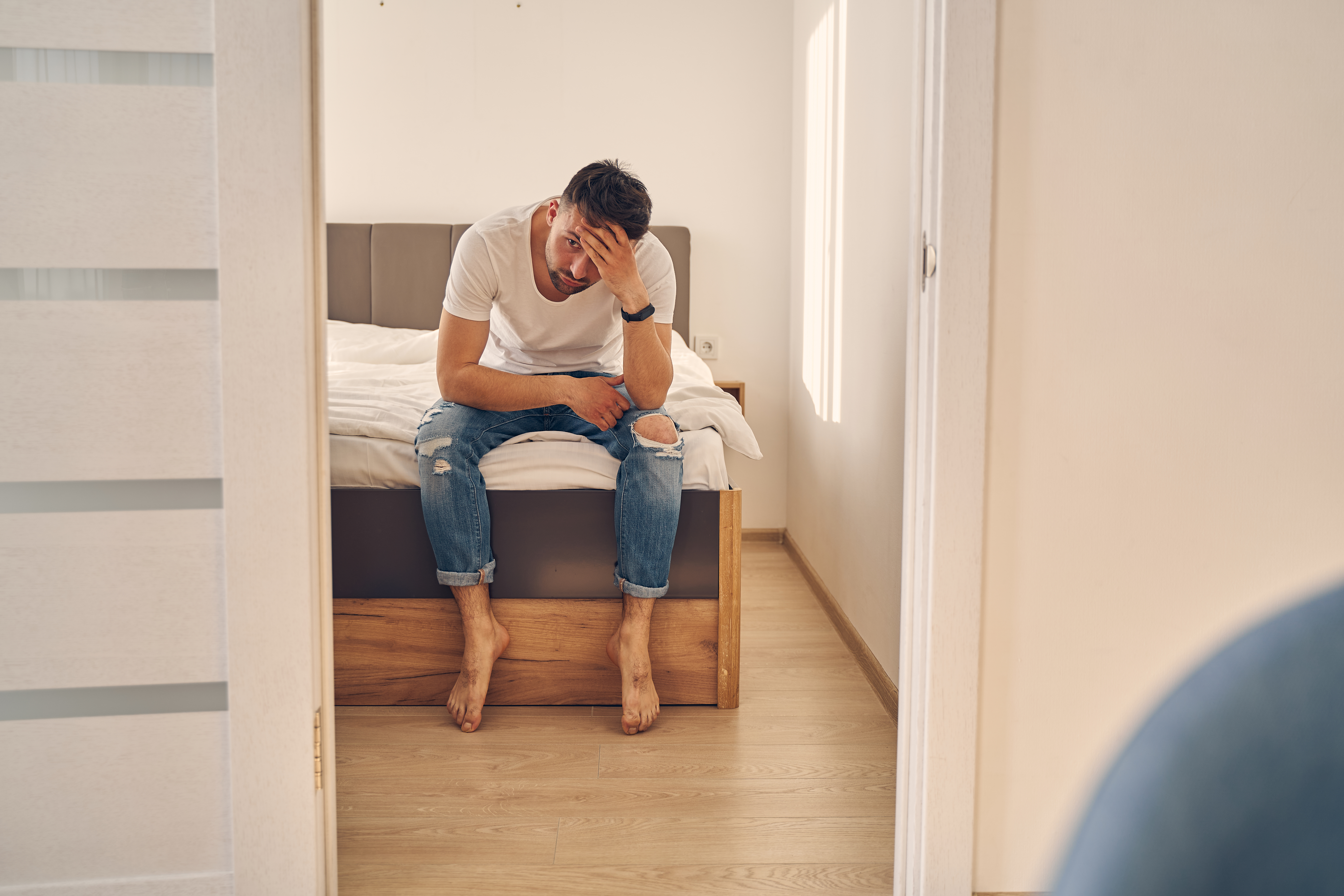 A troubled man sitting on the bed | Source: Shutterstock